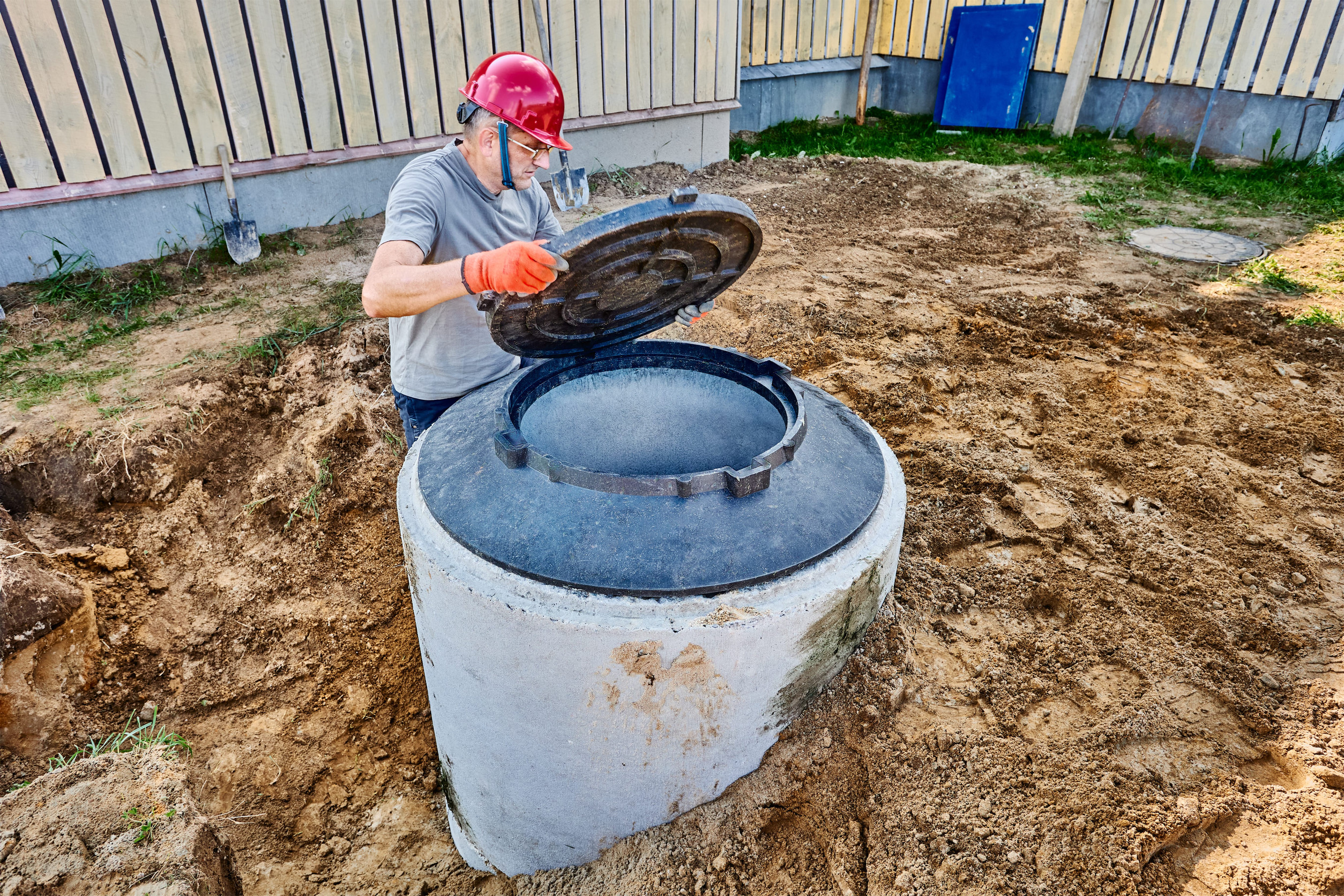 Installing manhole cover on septic tank made of concrete rings.